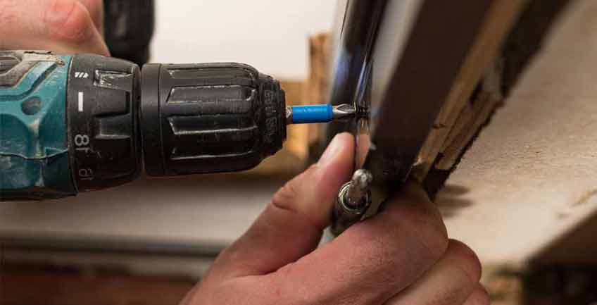Handyman repairing furniture with screwdriver in a Denver, Colorado interior design project